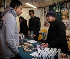 A group of men are standing around a table talking to each other.