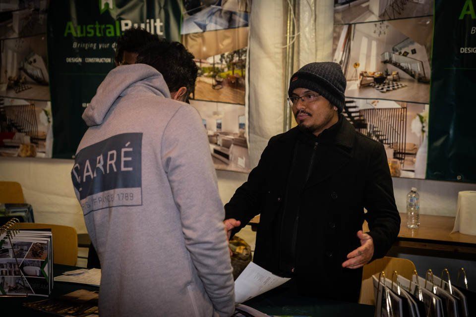 Two men are standing in front of a sign that says australprint