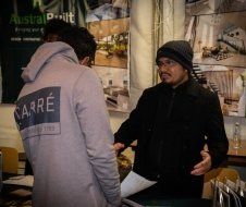 Two men are standing next to each other in front of a sign that says astralpoint.