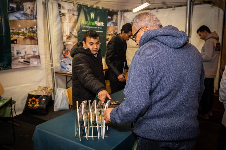 A man is standing at a table looking at a display of knives.
