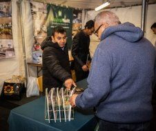 A group of men are standing around a table in a tent.