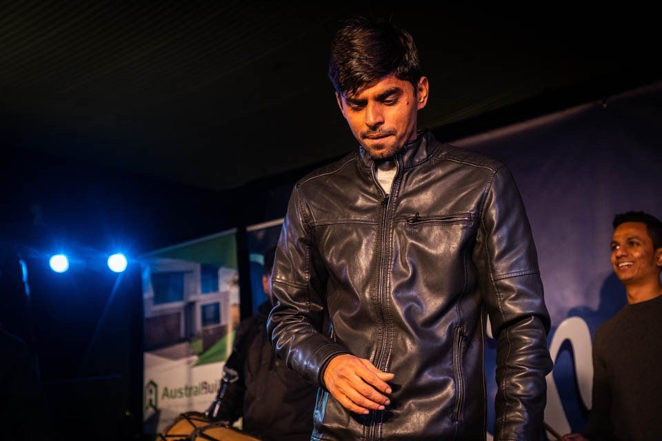 A man in a leather jacket is standing on a stage.