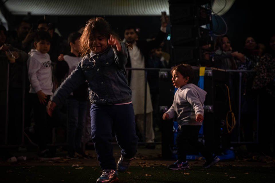 A little girl is dancing in front of a crowd of people.