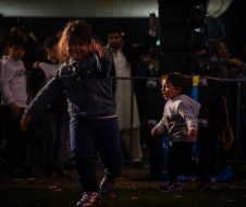 A group of children are playing soccer on a field at night.