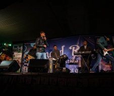 A group of people are standing on a stage playing instruments.