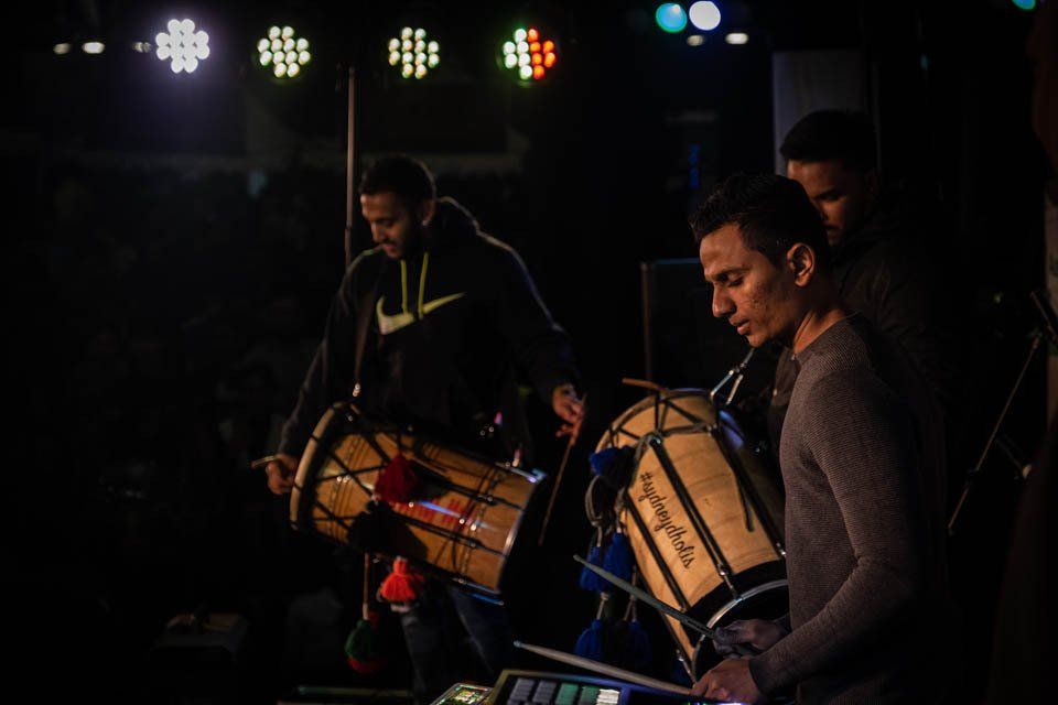A group of men are playing drums in a dark room.