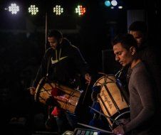 A group of men are playing drums in a dark room.