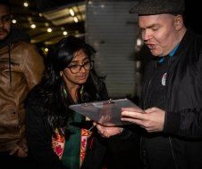 A man and a woman are standing next to each other looking at a clipboard.