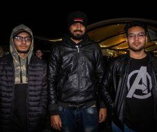 Three men are standing next to each other in a dark room.