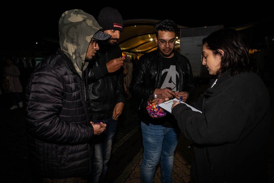 A group of people are standing in a dark room talking to each other.