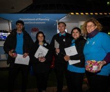 A group of people are standing next to each other holding boxes of candy.