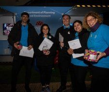 A group of people standing next to each other holding papers and candy.