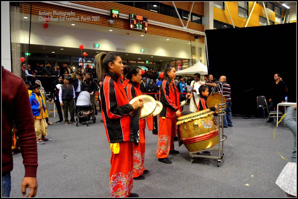 A group of children are playing drums in front of a crowd