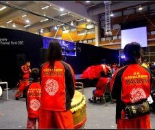 A group of people are standing in a room with a drum in the background.