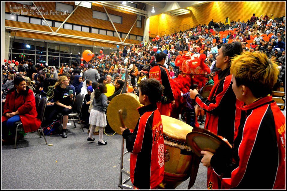 A group of people are playing drums in front of a crowd
