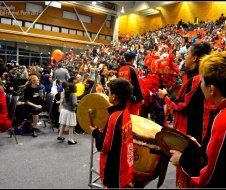 A group of people playing drums in front of a crowd
