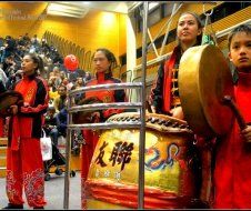 A group of people are playing drums in front of a crowd.