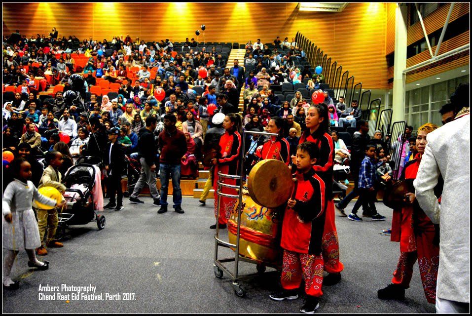 A group of children are playing drums in front of a crowd