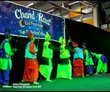 A group of people are dancing in front of a sign that says chand raat