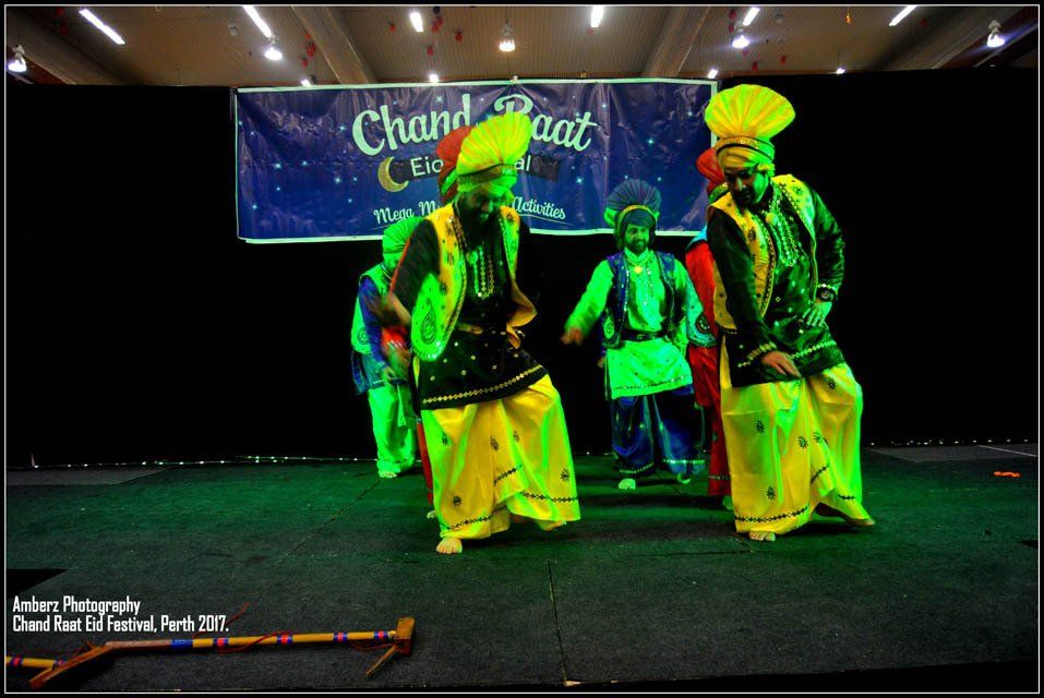 A group of people are dancing in front of a banner that says chand raat