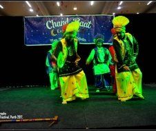 A group of people are dancing in front of a banner that says chand raat.