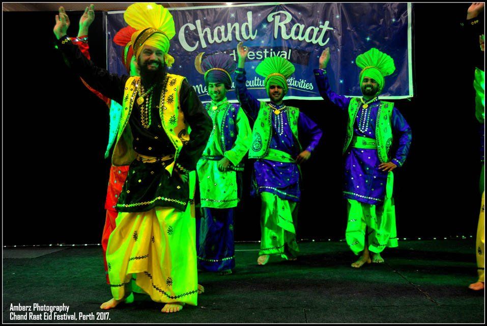 A group of men are dancing in front of a banner that says chand raat