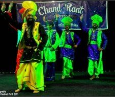 A group of people are dancing in front of a banner that says chand raat