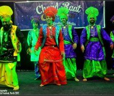 A group of men are dancing in front of a sign that says ' chord raat '