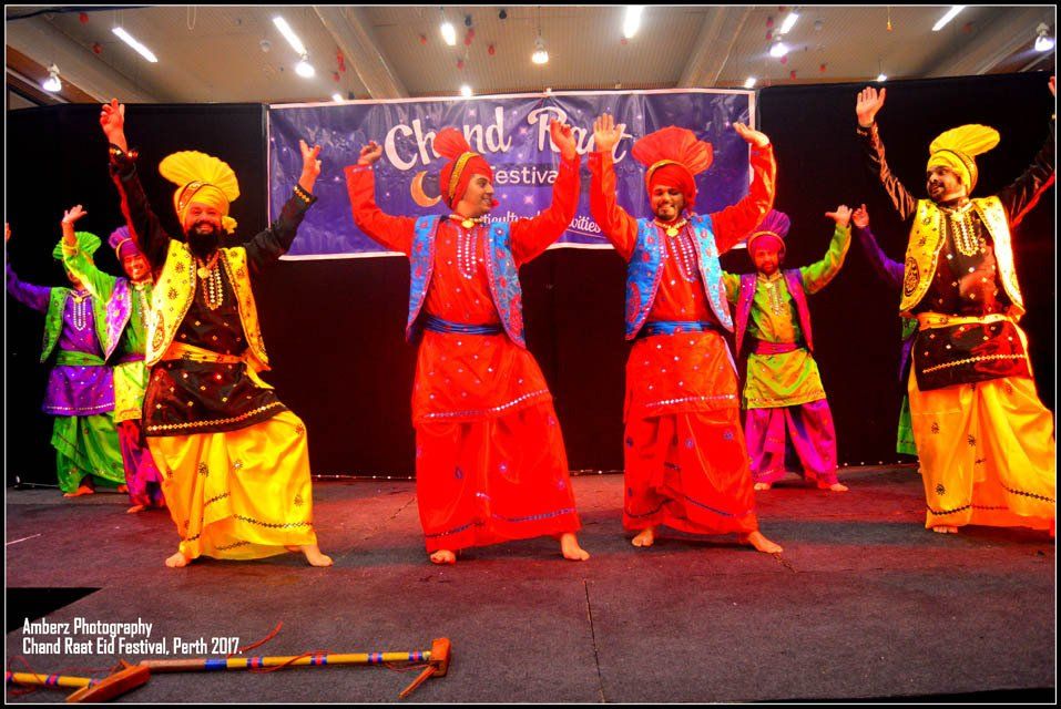 A group of people are dancing in front of a banner that says ' chandra ' on it