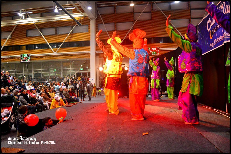 A group of people in colorful costumes are dancing on a stage