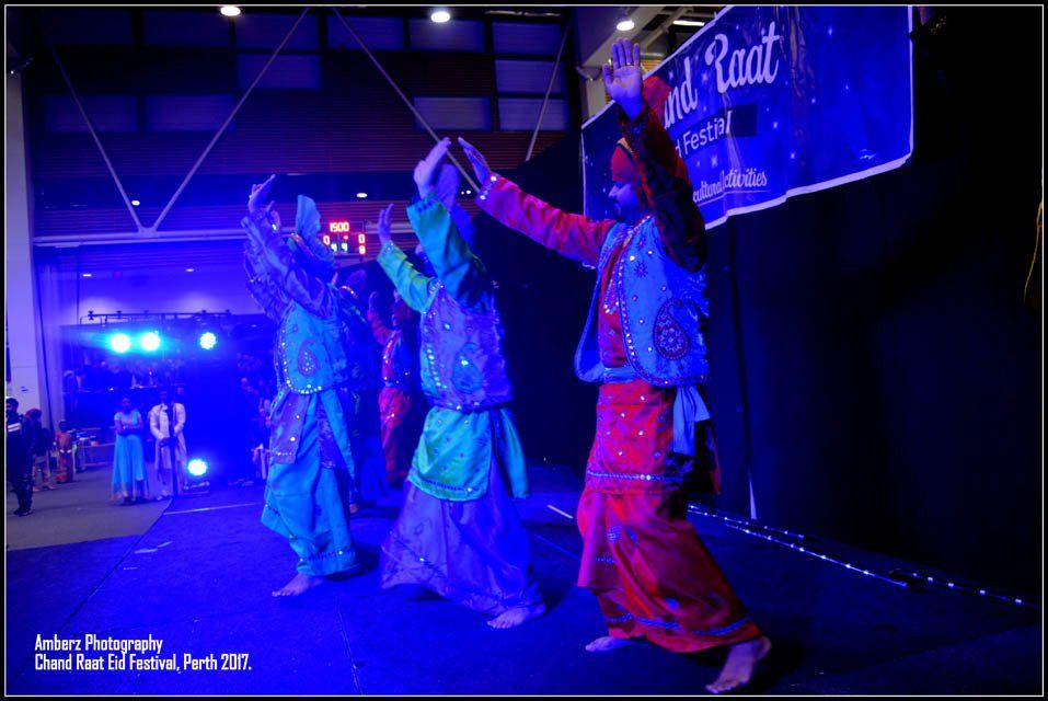 A group of people are dancing in front of a sign that says raat