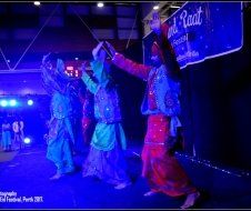 A group of people are dancing on a stage in front of a sign.