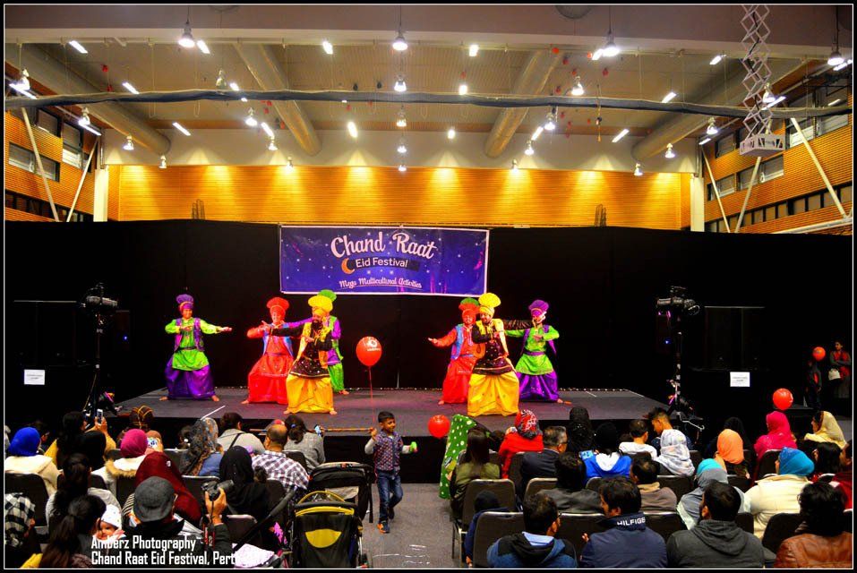 A group of people are dancing on a stage in front of a crowd.