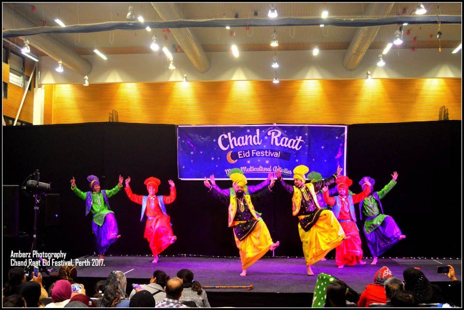 A group of people are dancing in front of a sign that says chand raat