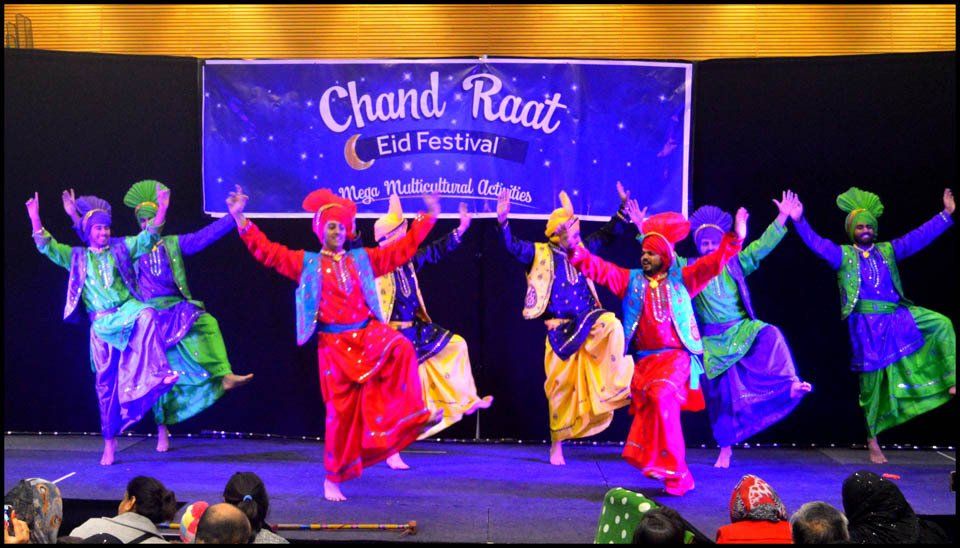 A group of people are dancing in front of a sign that says chand raat