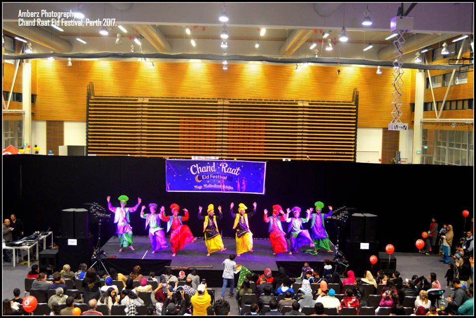 A group of people are dancing on a stage in front of a sign that says 