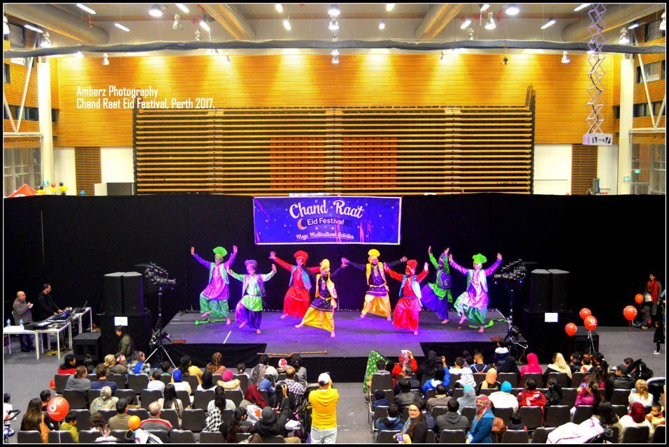 A group of people are dancing on a stage with a sign that says carnival bar