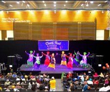 A group of people are dancing on a stage in front of a crowd.