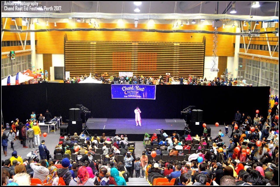 A large crowd of people are watching a performance in a large auditorium