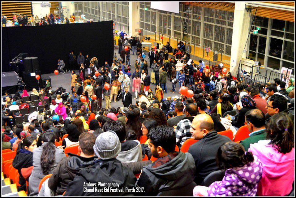 A crowd of people are gathered in an auditorium with a photo taken by a photographer