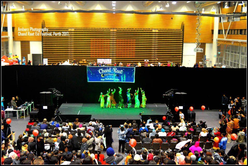 A group of people dancing on a stage with a sign that says christmas