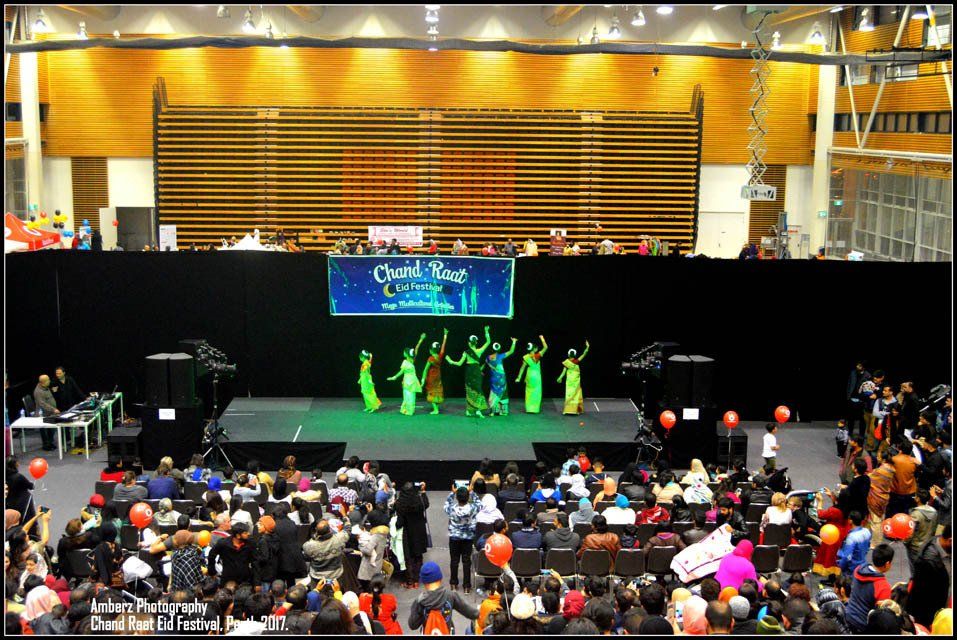 A group of people are dancing on a stage in front of a crowd