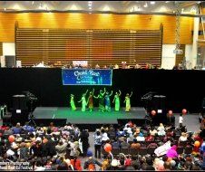 A group of people are dancing on a stage in front of a crowd.