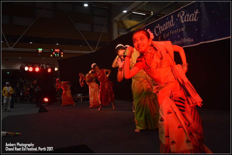 A group of women are dancing in front of a sign that says ' chandra raat '