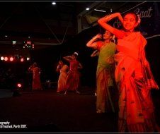 A group of women are dancing on a stage in a dark room.