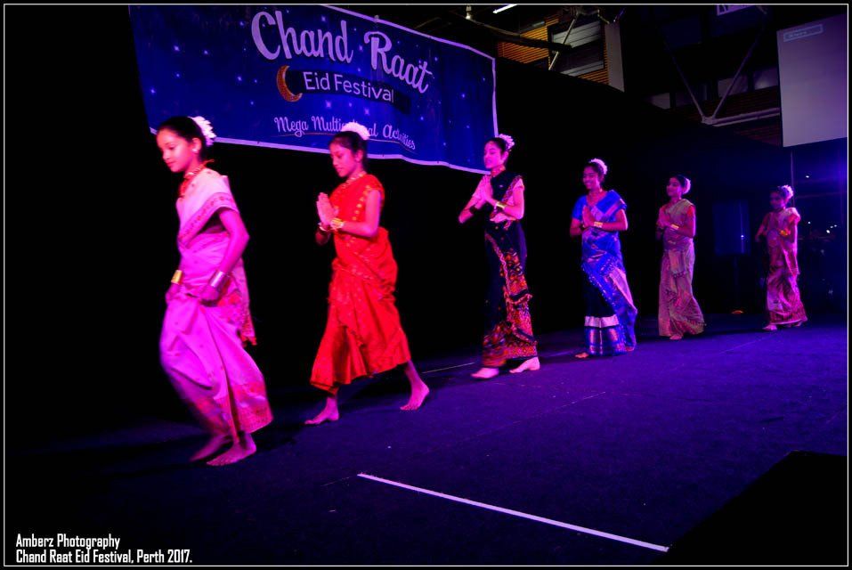 A group of girls are dancing in front of a sign that says chand raat