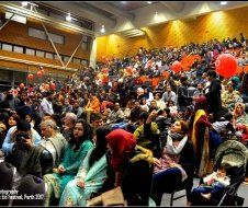 A large crowd of people are sitting in a stadium with balloons.