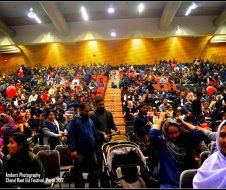 A large crowd of people are sitting in a large auditorium.