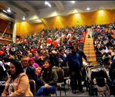 A large crowd of people are sitting in a large auditorium.