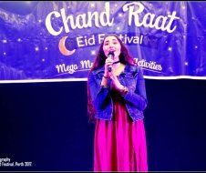 A woman in a pink dress is singing into a microphone.